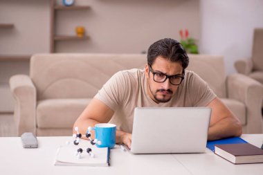 Genç erkek öğrenci salgın sırasında evde çalışıyor.