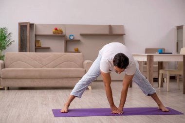 Genç adam evde spor yapıyor.