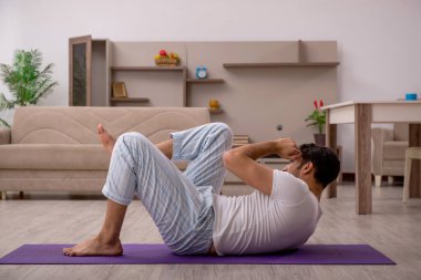 Genç adam evde spor yapıyor.