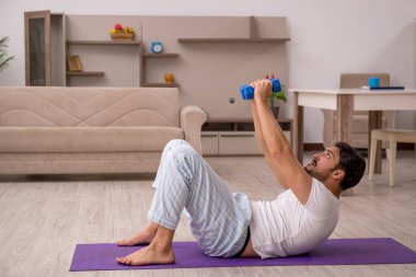 Genç adam evde spor yapıyor.