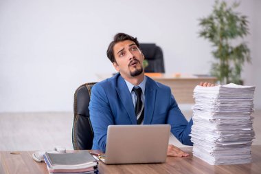 Ofisteki aşırı işten memnun olmayan genç bir erkek işçi.