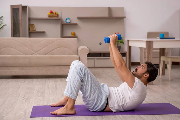 Jovem fazendo exercícios esportivos em casa — Fotografia de Stock