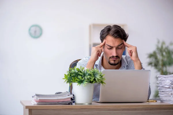 Jonge mannelijke werknemer ongelukkig met overmatig werk in het kantoor — Stockfoto