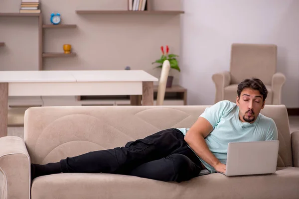 Joven sentado en el sofá con ordenador en casa — Foto de Stock