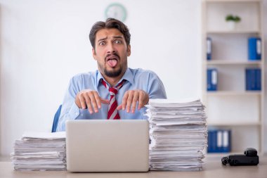 Genç bir erkek çalışan ve ofiste çok fazla iş var.