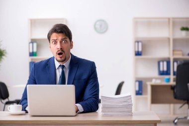 Genç bir erkek çalışan ve ofiste çok fazla iş var.