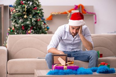 Genç adam Noel 'i evde yalnız kutluyor.