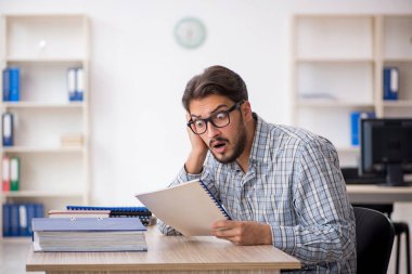 Genç erkek çalışan ofiste oturuyor.