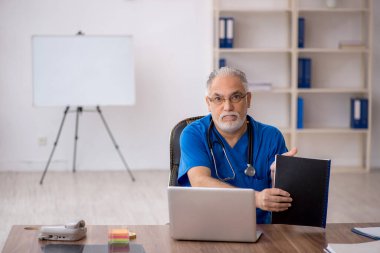 Klinikte çalışan yaşlı erkek doktor.