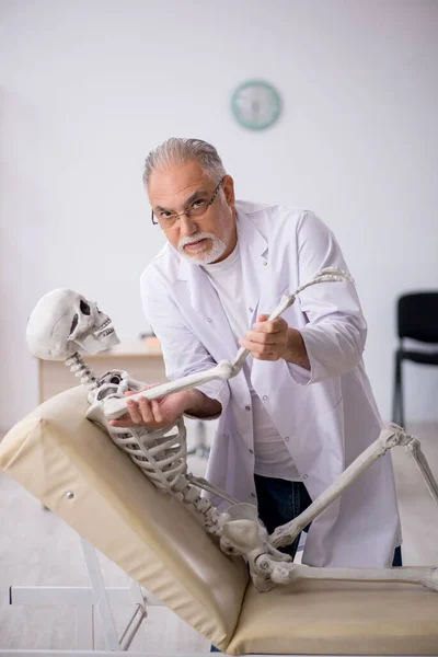 Viejo doctor con esqueleto en la clínica —  Fotos de Stock