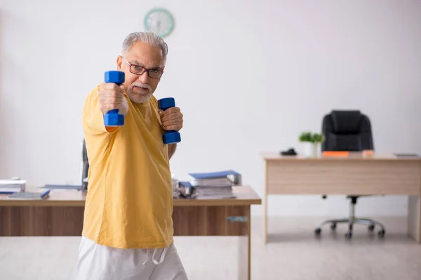 Velho empresário empregado fazendo exercícios esportivos no escritório — Fotografia de Stock