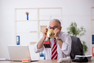 Eski erkek çalışana altın kupa veriliyor.