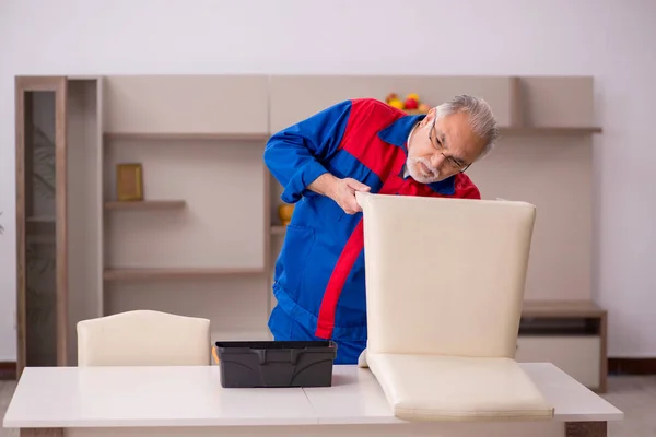 Vieux charpentier masculin réparer chaise à l'intérieur — Photo