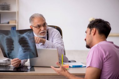 Genç erkek hasta yaşlı erkek doktor radyolojisti ziyaret ediyor.