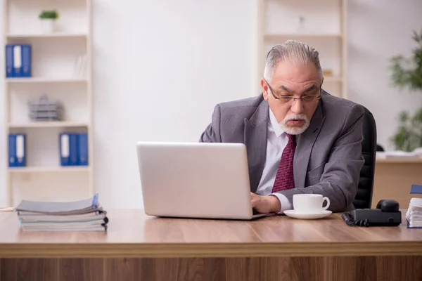 Oude mannelijke werknemer drinkt thee tijdens de pauze — Stockfoto