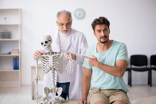 Jonge mannelijke patiënt bezoekt oude mannelijke arts — Stockfoto