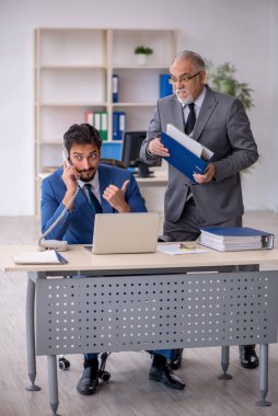 Yaşlı erkek patron ve ofiste çalışan genç erkek çalışan.