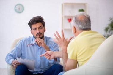 Yaşlı adam genç erkek psikoterapisti ziyaret ediyor.