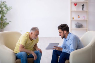 Yaşlı adam genç erkek psikoterapisti ziyaret ediyor.