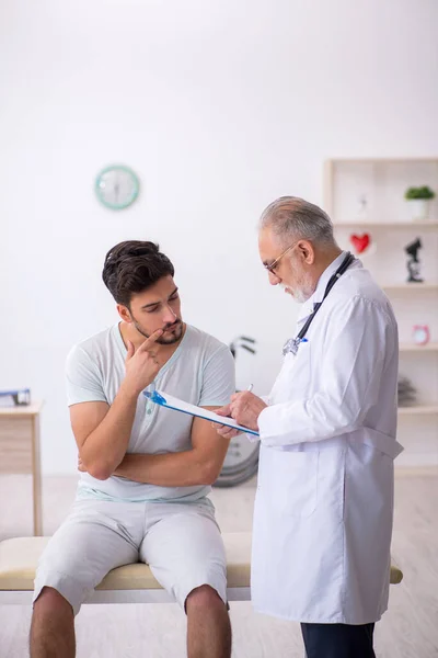 Jeune patient de sexe masculin visitant un vieux médecin — Photo