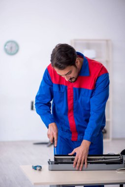 Klimayı tamir eden genç bir erkek tamirci