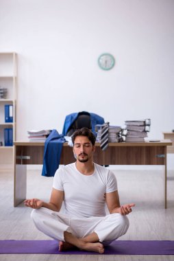 Genç erkek çalışan ofiste spor egzersizleri yapıyor.