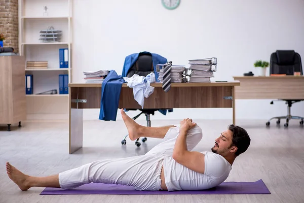 Jovem funcionário do sexo masculino fazendo exercícios esportivos no escritório — Fotografia de Stock