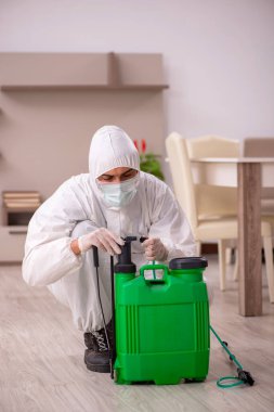 Genç erkek müteahhit evde haşere kontrolü yapıyor.