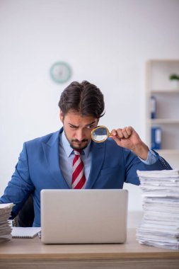 Genç bir erkek çalışan ve ofiste çok fazla iş var.