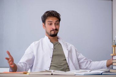 Genç erkek kimyacı öğretmen beyaz tahtanın önünde.