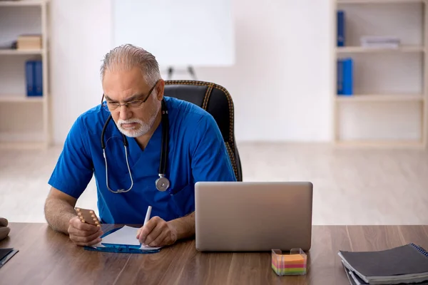 Gammal manlig läkare som arbetar på kliniken — Stockfoto