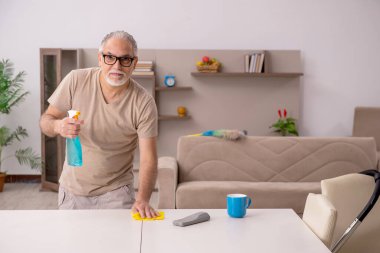 Yaşlı adam evde ev işi yapıyor.