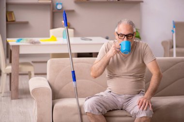 Yaşlı adam evde ev işi yapıyor.