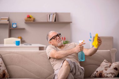 Yaşlı adam evde ev işi yapıyor.