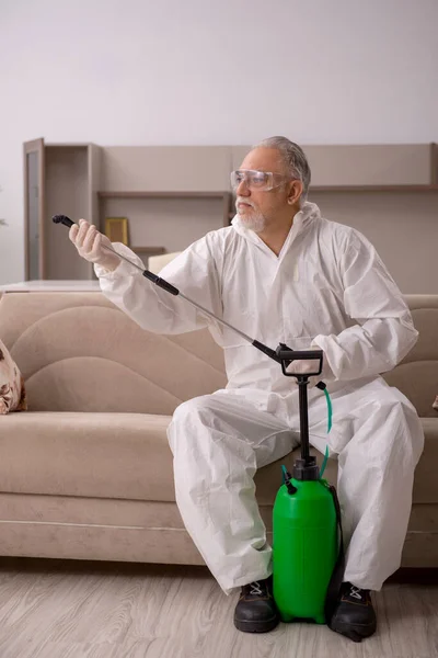 Velho empreiteiro masculino fazendo controle de pragas em casa — Fotografia de Stock