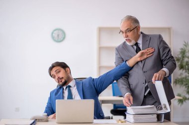 Yaşlı erkek patron ve ofiste çalışan genç erkek çalışan.