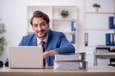 Genç bir erkek çalışan ve ofiste çok fazla iş var.