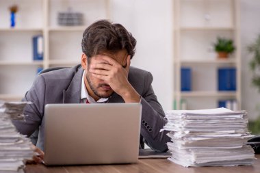 Ofisteki aşırı işten memnun olmayan genç bir erkek işçi.