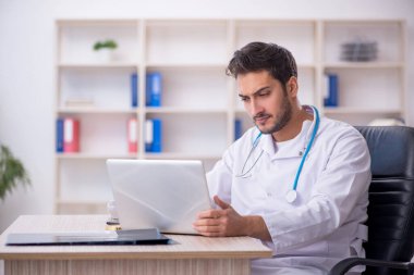 Klinikte çalışan genç erkek doktor.