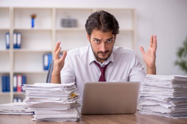 Genç bir erkek çalışan ve ofiste çok fazla iş var.