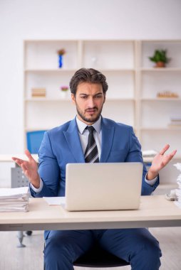 Genç bir erkek çalışan ve ofiste çok fazla iş var.