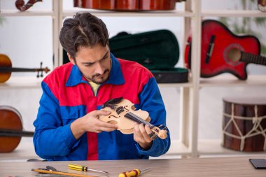 Genç adam atölyede müzik aletlerini tamir ediyor.