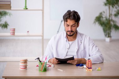 Klinikte çalışan genç erkek dişçi.