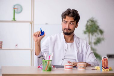 Klinikte çalışan genç erkek dişçi.