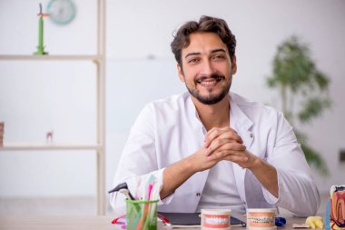 Klinikte çalışan genç erkek dişçi.