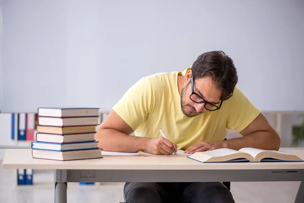 Ung manlig student förbereder sig för tentor i klassrummet — Stockfoto