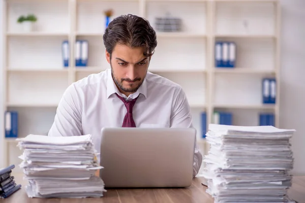 Joven empleado masculino y demasiado trabajo en la oficina — Foto de Stock