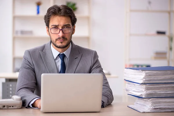 Joven empleado masculino y demasiado trabajo en la oficina — Foto de Stock