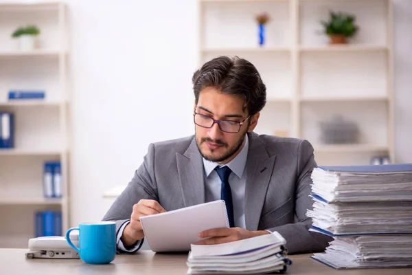 Ung manlig anställd och för mycket arbete på kontoret — Stockfoto