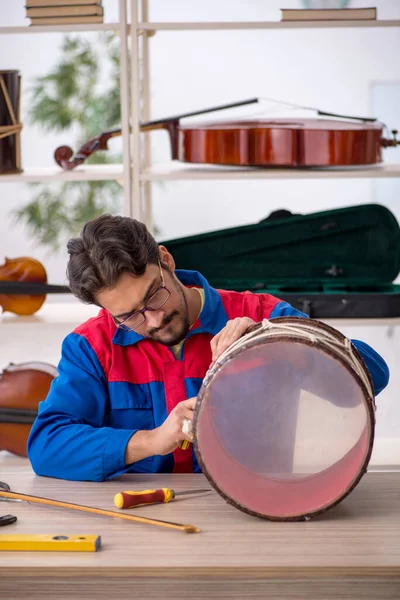 Mladý muž opravuje hudební nástroje v dílně — Stock fotografie